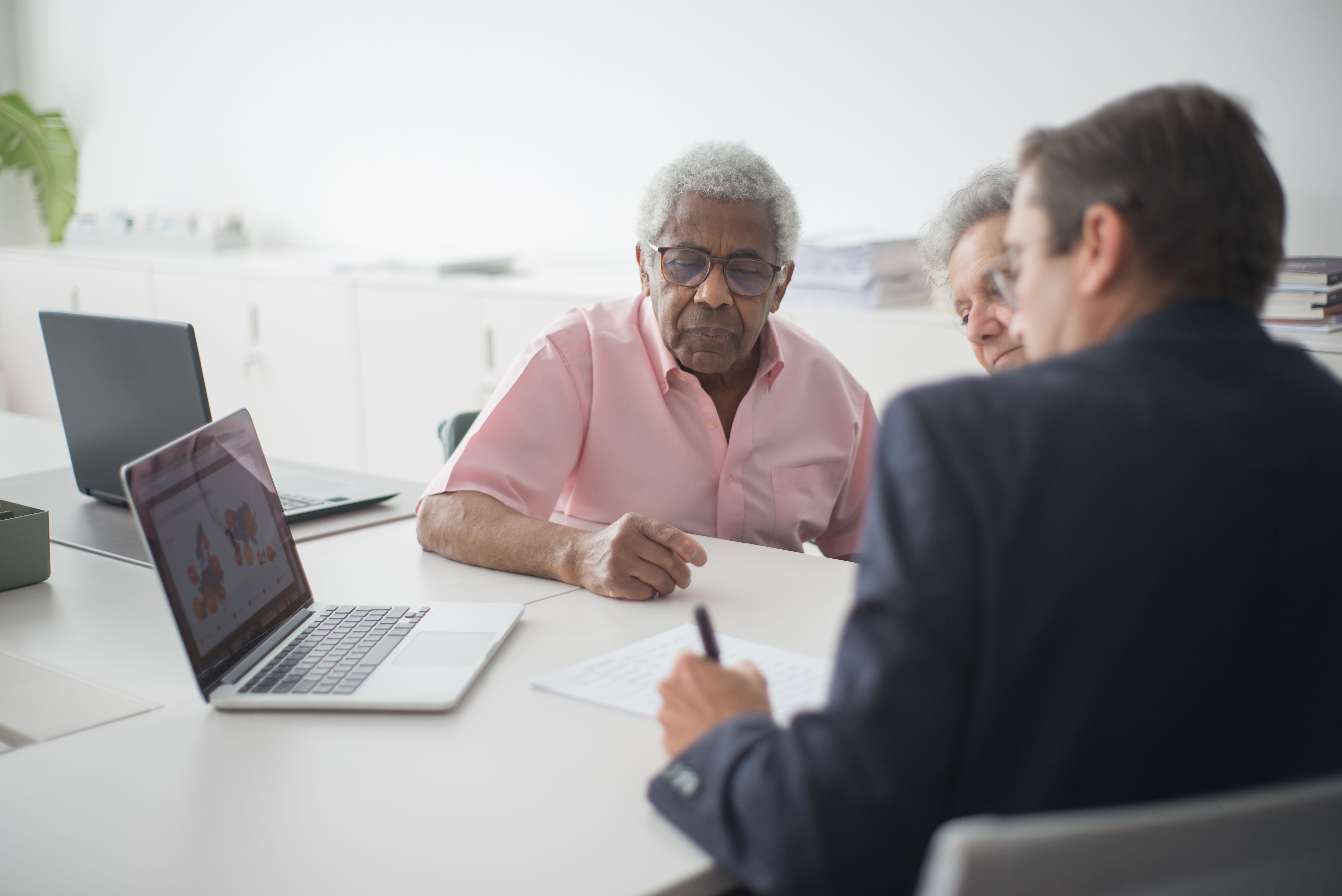 Un senior examine ses documents et relevés devant son ordinateur portable